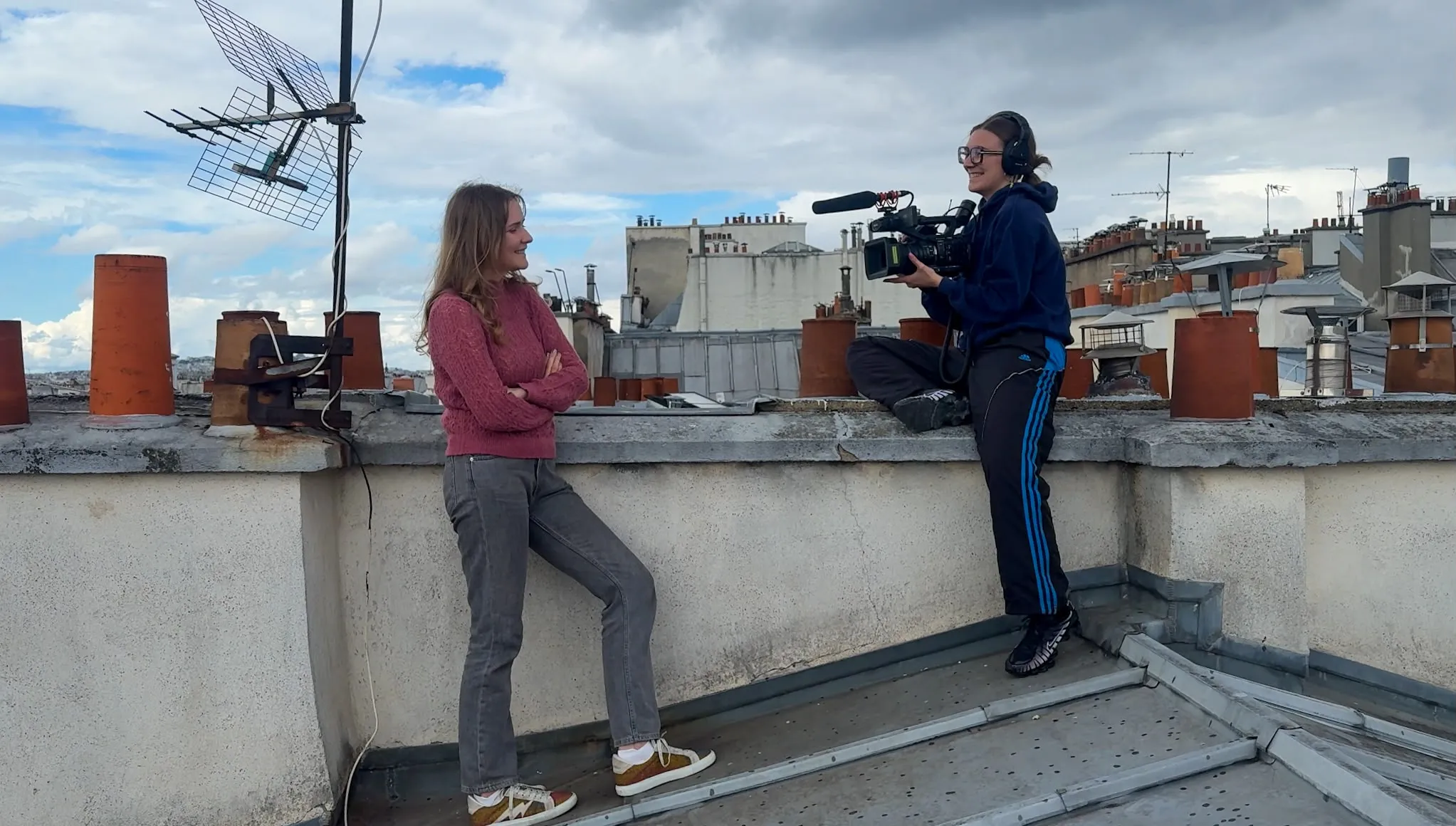 A rooftop shoot in Paris — Mariia Ko in front of the camera, with an operator filming across the zinc roofs